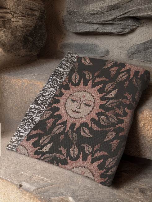 Luxurious woven cotton throw featuring dreamy blush pink sun faces with closed eyes against black background with delicate ray patterns and elegant fringe trim. Perfect celestial wall hanging, witchy bedroom decor, or dark academia throw blanket.